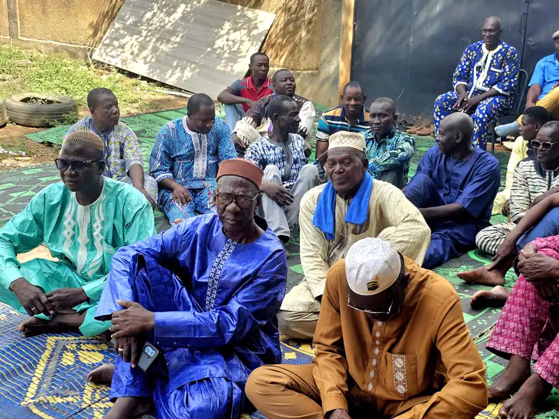 Des aînés en boubou assis sur des nattes, lors d'une réunion de famille.