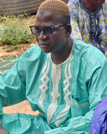 Un homme en boubou turquoise brodé.
